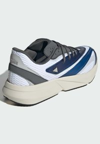 Sneaker featuring a white mesh upper, dark gray accents, and a blue stripe. Thick off-white sole with slight texture and branding on heel.