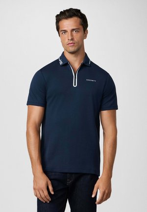 Polo shirt blu navy con colletto a zip e accentature bianche. Presenta maniche corte e un logo sul petto. Realizzato in un tessuto morbido e traspirante.