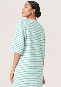 Rochie cu dungi, de culoare albă și albastră deschisă, cu dungi verticale, mâneci scurte și o croială lejeră. Material moale, ușor, cu o textură netedă.