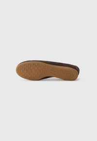 Chaussure slip-on en daim brun avec une semelle extérieure en caoutchouc flexible présentant des motifs de grip circulaires pour une meilleure traction. Ne comporte pas de décorations ni de matériel visible.