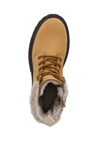 Tan leren boot met bruine rubberen zool, voorzien van beige nepbont voering, ronde neus en bruine veters. Zichtbaar logo aan de binnenkant.