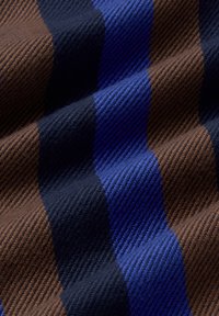 Tessuto textured con strisce alternate di blu profondo, blu navy e marrone in un design tessuto, che mostra un motivo distintivo e una morbidezza.