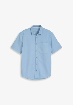 Chemise à manches courtes bleu clair avec tissu texturé et une poche poitrine unique, affichée à plat sur un fond blanc.