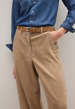 Beige Cordhosen mit vertikalen Streifen, mit lässiger Passform, seitlichen Taschen und einem braunen Ledergürtel auf einem Jeanshemd.