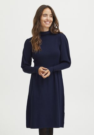 Knit dress in navy blue with a high neckline and puffed long sleeves. Features a fitted bodice and a loose skirt with a smooth texture.
