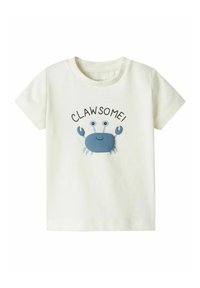 T-shirt in cotone color crema chiaro con grafica di un granchio blu e la parola "CLAW-SOME!" stampata sopra in nero. Design con maniche corte e colletto a girocollo.