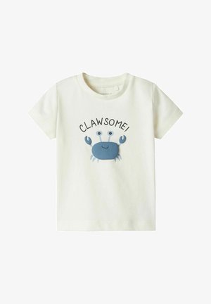 T-shirt in cotone color crema chiaro con grafica di un granchio blu e la parola "CLAW-SOME!" stampata sopra in nero. Design con maniche corte e colletto a girocollo.