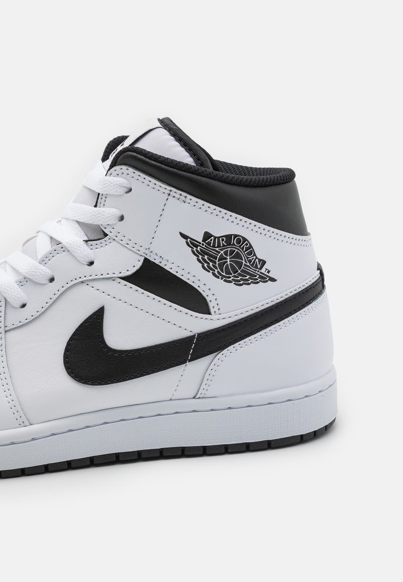 Zapatilla alta de cuero blanca con detalles en negro, que presenta un logotipo distintivo, cordones redondos y una suela de goma texturizada.