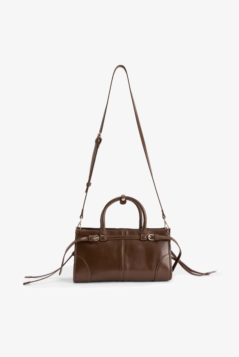 Brown leather handbag with a structured shape, top handles, removable shoulder strap, and buckle accents. Smooth texture with detailed stitching.