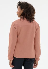 Fleece jas in zachtroze met een gemêleerd lichaam, glad bovenpaneel en een relaxte pasvorm. Heeft lange mouwen en een ronde onderkant.