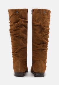 Bottes hauteur genou en daim marron avec texture froncée, une fermeture éclair latérale et un talon noir bas. Caractérisées par des coutures lisses et un design à bout rond.