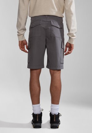 Pantaloni cargo grigi con molteplici tasche, realizzati in tessuto leggero. Presentano orli arrotolati e una vestibilità comoda, abbinati a scarpe nere e calzini bianchi.