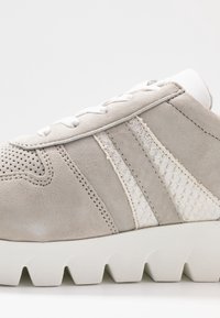 Vaaleanharmaat mokkasaappaat valkoisilla nauhoilla, teksturoidut sivuviivat, rei'itetty varvasosa ja paksu uritettu valkoinen pohja.