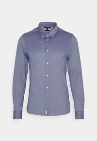 Camicia da uomo con bottoni in tessuto blu medio, caratterizzata da colletto classico, maniche lunghe, bottoni bianchi e un piccolo logo sul petto.