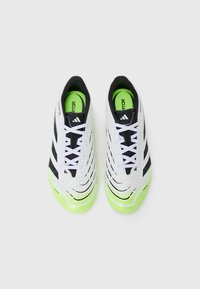 White and black athletic shoes with a textured surface, featuring green accents and a lace-up design. Predominantly sleek and modern shape.