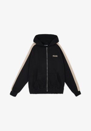 Sudadera negra con cremallera y capucha, con rayas beige en las mangas, bolsillos delanteros, puños y dobladillo elásticos, y texto "PEGADOR" en el lado izquierdo del pecho.