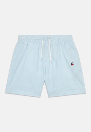 Vaaleansiniset uimashortsit, joissa on valkoiset pystysuorat raidat, kuminauhavyötärö, kiristysnauha ja kirjailtu "Tommy Hilfiger" -logon yksityiskohta.