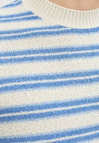 Gros plan d'un tissu tricoté avec des rayures horizontales bleues et blanches et un col côtelé beige.