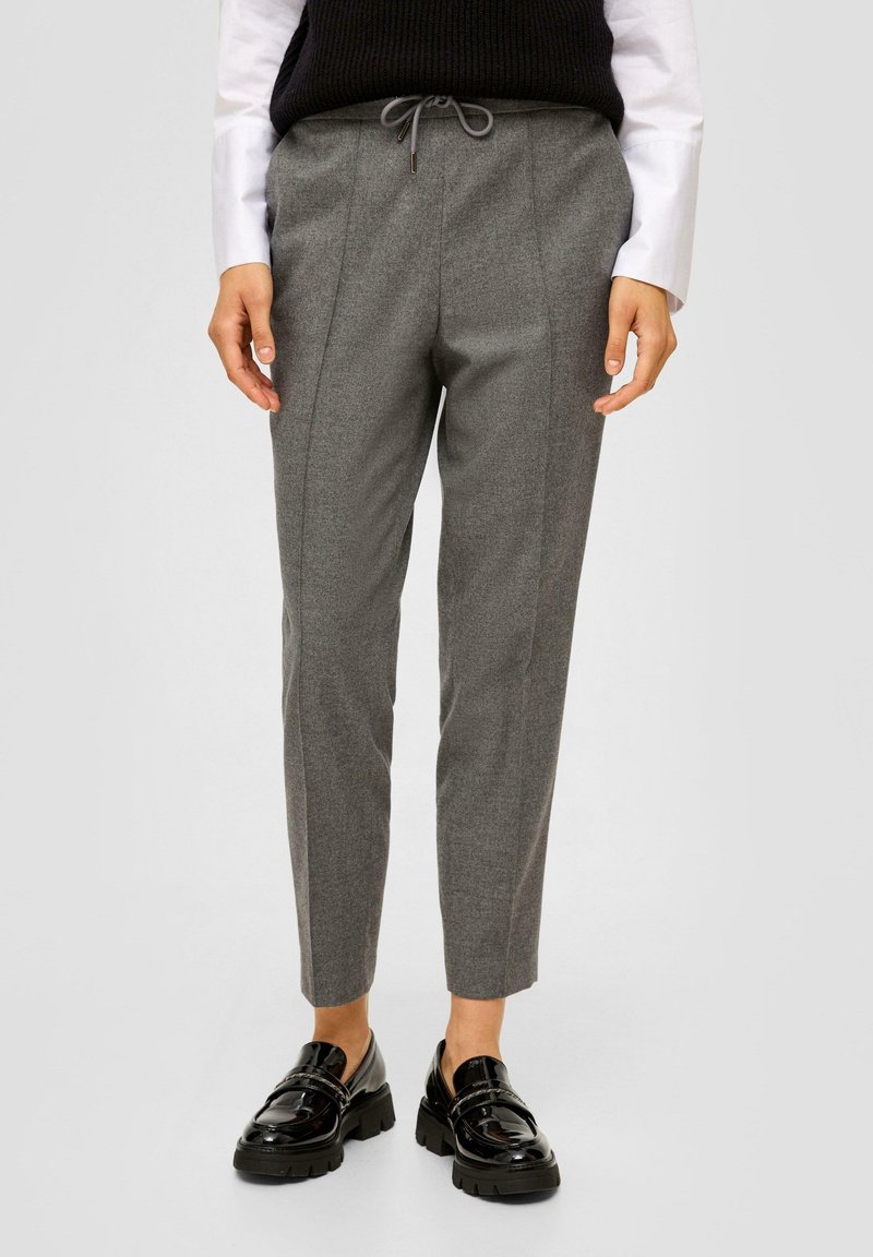 Pantalon gris ajusté au tissu lisse, doté d'une taille à cordon et de deux coutures verticales. Assorti avec des mocassins noirs épais.