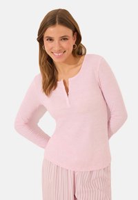 Light pink long-sleeve top with a ribbed texture, henley neckline, and three small buttons. Model wearing matching striped pajama bottoms.