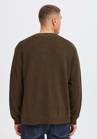 Brown knitted sweater with long sleeves and a crew neck, featuring a textured fabric and a relaxed fit, seen from the back.