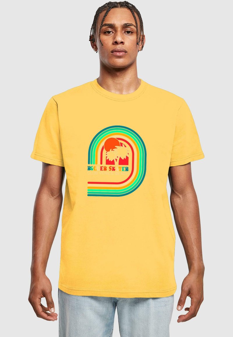 Geltona medvilnės marškinėliai su daugiakryptėm grafikomis, kuriose vaizduojami palmių medžiai ir saulė, papuošti tekstu "ROLLER SKATER CLUB VENICE BEACH."