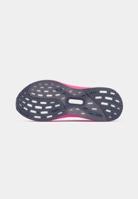 Sola de um ténis de corrida rosa mostrando uma aderência pautada em preto e branco com sulcos texturizados contra um fundo branco simples.
