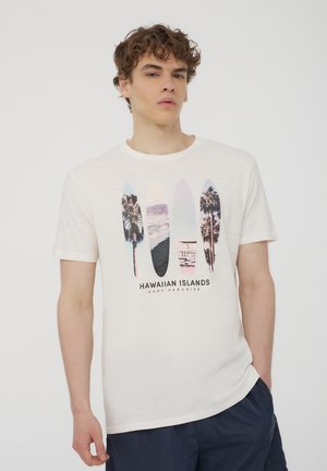 T-shirt bianco a maniche corte con una grafica di tavole da surf colorate e palme, con la scritta "PARADISO DEL SURF DELLE ISOLE HAWAIANE" stampata sotto.