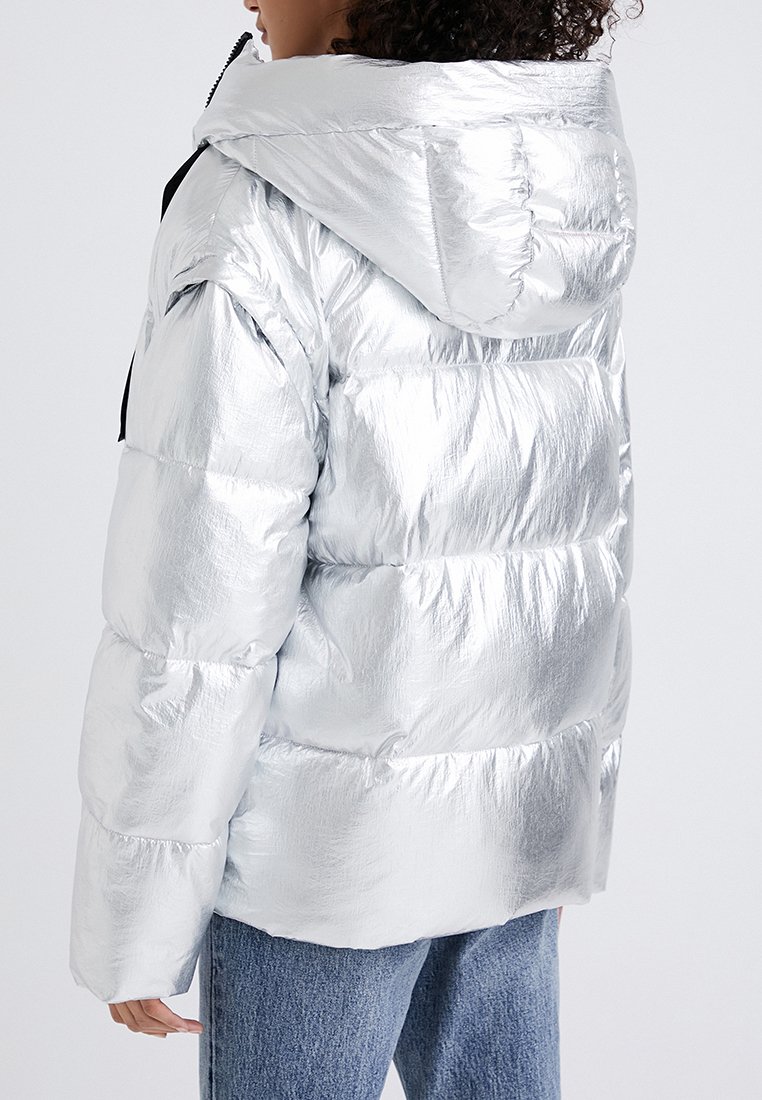 Srebrna kurtka puchowa z błyszczącym, metalicznym wykończeniem, z kapturem i pikowanym wzorem. Zawiera elastyczny dół oraz czarne akcenty z metalu.