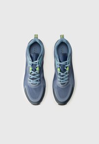 Modri športni copati z teksturiranim zgornjim delom, zelenimi akcenti in belimi gumijastimi podplati, s sistemom vezalk in zanko za poteg na peti.