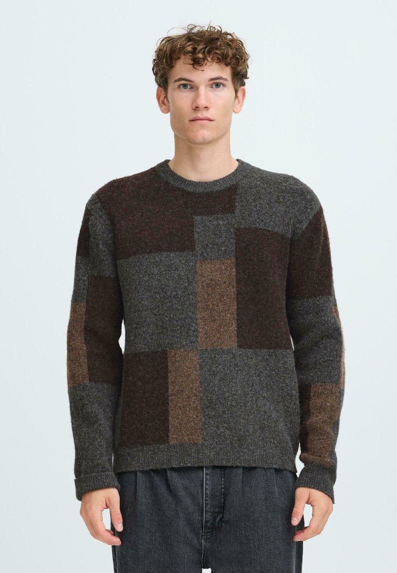 Strickpullover mit einem Patchwork-Design in Grautönen, Braun und Rost. Er hat einen runden Ausschnitt und gerippte Bündchen, mit einer strukturierten Oberfläche.