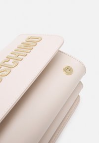 Blushfärgad konstläderplånbok med präglad guld "Moschino"-logotyp, tryckknappsöppning och slät yta med snygg sömnad.