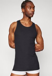 Black ribbed tank top with a scoop neckline and wide shoulder straps. Features a fitted silhouette and soft texture.