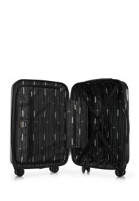 Valise noire avec coque rigide, ouvertures zippées et sangles croisées intérieures. Doublée d'un motif rayé en blanc et gris. Quatre roues.