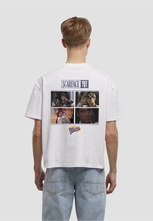Hvid bomulds-T-shirt med et collage af scener fra filmen "Scarface" på ryggen, med "Scarface"-logo og "Welcome to Miami"-detalje.