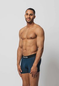 Marineblaue Boxershorts mit einem schwarzen elastischen Bund, auf dem der Text "SNOCKS" steht. Der Stoff wirkt glatt und dehnbar und passt eng an.