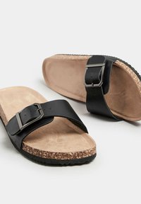 Sandali neri in pelle con una larga fascia caratterizzata da una fibbia in argento, una soletta in sughero texturizzato e una suola in gomma. Intersuola morbida simile alla suede.