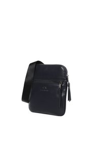 Borsa a tracolla in pelle blu navy con una superficie liscia, chiusura con zip, tasca frontale e tracolla regolabile. Dotata di logo impresso sul davanti.