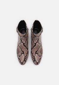 Bottines en peau de serpent avec un mélange de motifs beige et brun foncé, dotées d'un col haut et d'accents en métal argenté.