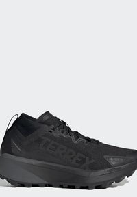 Chaussure de trail running TERREX noire avec tige imperméable GORE-TEX et semelle amortissante Lightstrike, vue de côté sur fond uni.
