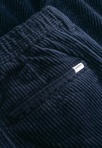 Navy corduroy broek met een gestructureerd ribbelpatroon, met zichtbare zakdetails en een klein label met de tekst "GABBA."