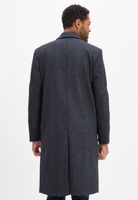 Donkergrijze herringbone jas met een getailleerd ontwerp, lange mouwen en een enkele vent aan de achterkant. Gladde textuur en klassieke kraagdetails.