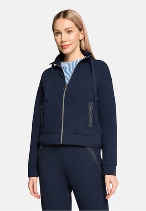Navy cropped zip-up sweatshirt with a high collar, drawstring, and studded accents on pockets. Soft fabric with a relaxed fit.