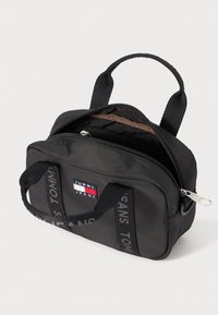 Zwarte nylon tas met een rechthoekige vorm, dubbele textuur handvatten, een ritssluiting aan de bovenkant en een logopatch met rode, witte en blauwe accenten.