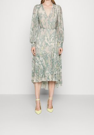 Kes dress setengah panjang yang transparan dengan cetakan paku-pakis hijau, leher V, lengan baju panjang berbentuk puff, pinggang cinch, dipadukan dengan sepatu hak tinggi ankel berwarna kuning pucat.