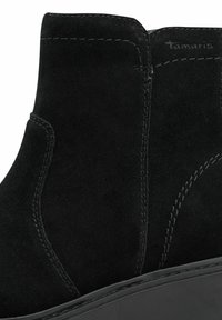 Czarne zamszowe botki za kostkę z okrągłym noskiem, przeszyciami oraz delikatną platformą. Widoczna nazwa marki "Tamaris" po boku.