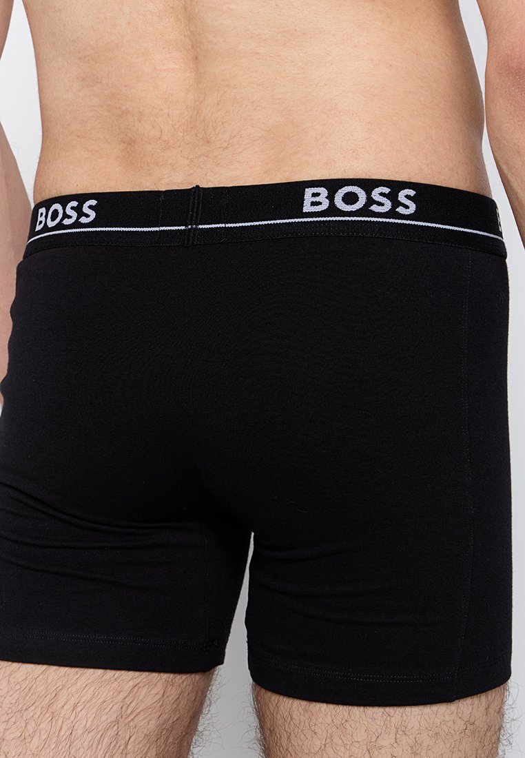 Boxers noirs en coton avec une coupe ajustée. Dotés d'une large ceinture noire avec le logo "BOSS" en blanc. Texture lisse sans motifs.