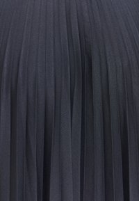 Tejido negro con pliegues que exhibe finos pliegues verticales, hecho de un material suave con textura y un acabado liso.