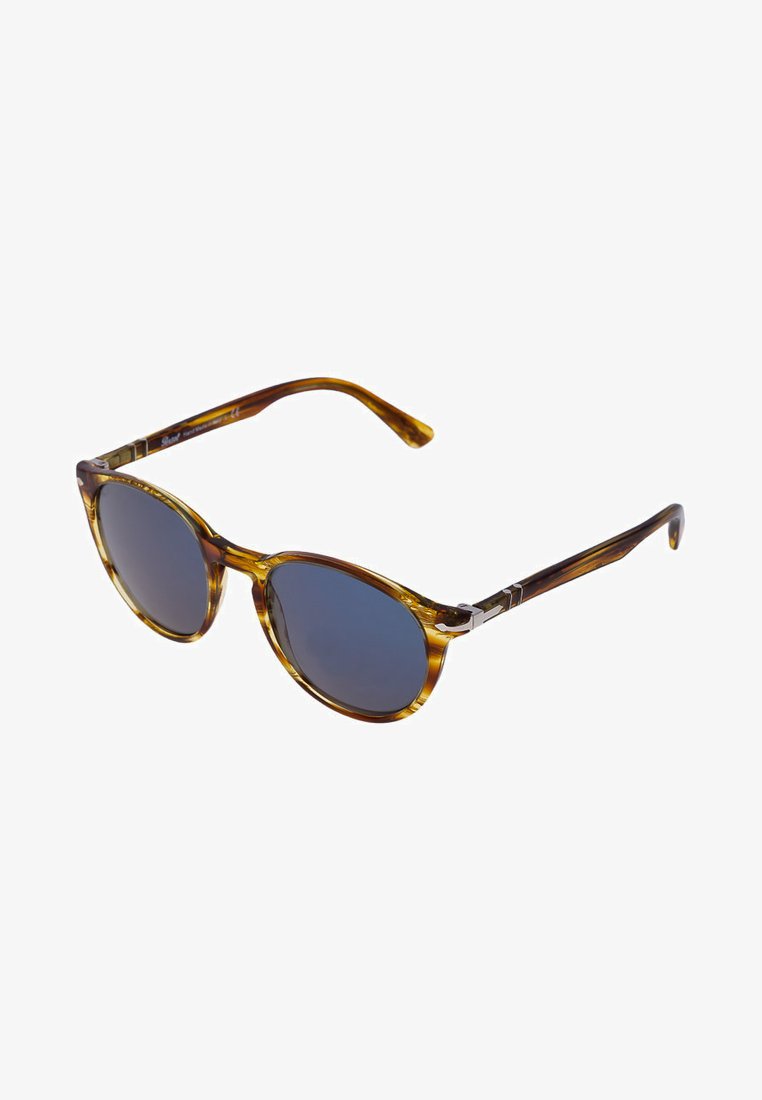 Óculos de sol tartaruga com lentes redondas, tom de azul escuro e detalhes em metal nas hastes. Armação elegante com acabamento brilhante.