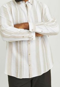 Koszula w paski, button-up, w kolorach beżowym i białym, wykonana z lekkiego materiału. Posiada długie rękawy, zapięcie na guziki przy mankietach oraz zaokrąglony dół.